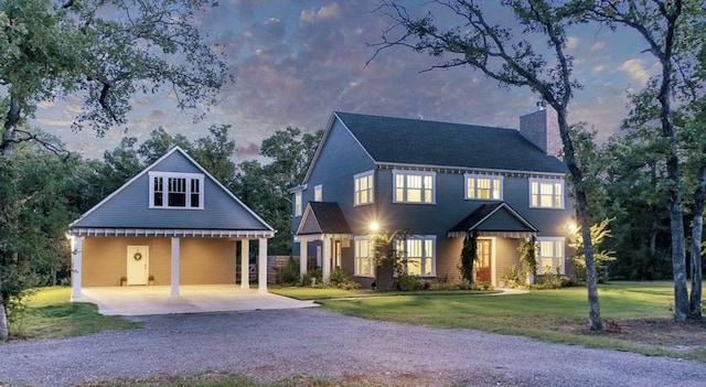 view of front of home featuring a lawn, a carport, a chimney, and gravel driveway