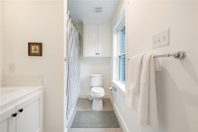 bathroom with vanity, plenty of natural light, toilet, and visible vents