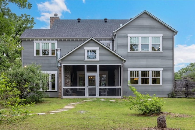 back of house with a lawn, a chimney, a sunroom, and a shingled roof