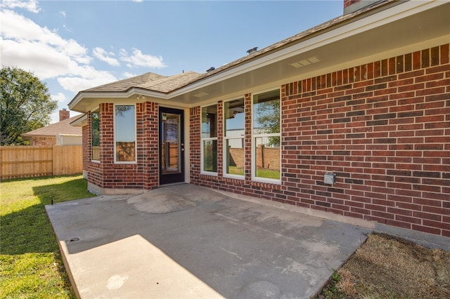 back of house featuring a fenced backyard, a chimney, brick siding, a lawn, and a shingled roof