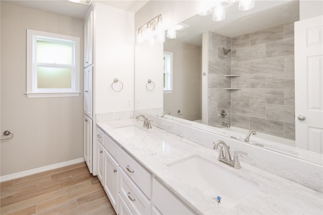 bathroom featuring a garden tub, wood finished floors, a sink, and double vanity