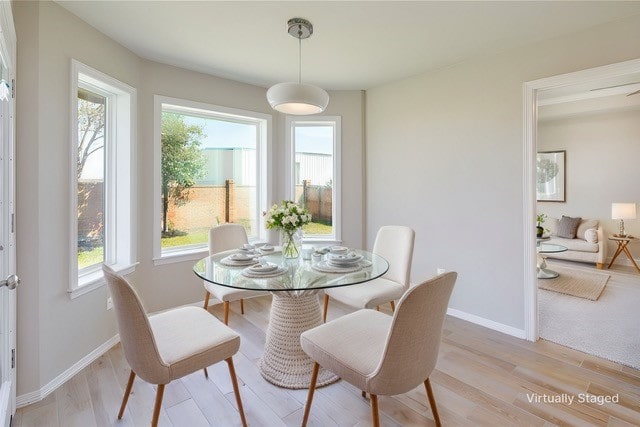 unfurnished room featuring baseboards, light wood finished floors, and plenty of natural light