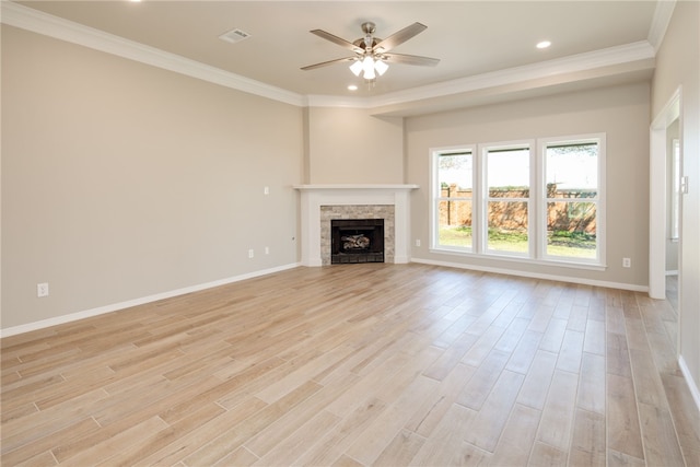 unfurnished living room featuring light wood-type flooring, ornamental molding, and a tiled fireplace