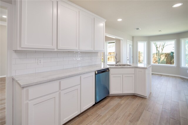 kitchen featuring backsplash, white cabinets, sink, stainless steel dishwasher, and light wood-type flooring