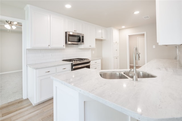 kitchen featuring a peninsula, a sink, visible vents, light stone counters, and appliances with stainless steel finishes