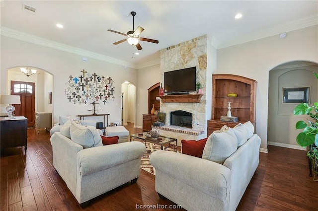 living room featuring ceiling fan with notable chandelier, dark hardwood / wood-style flooring, a fireplace, and crown molding