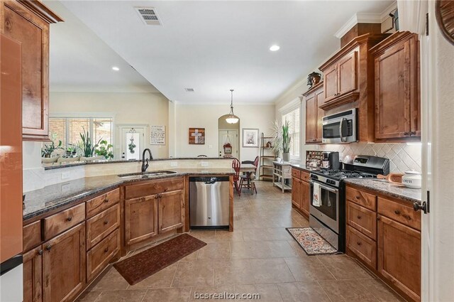 2000 Cassandra Ct, Bryan, TX 77807 - kitchen with appliances with stainless steel finishes, a sink, decorative backsplash, brown cabinets, and dark stone counters