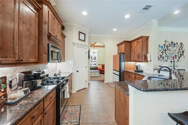 2000 Cassandra Ct, Bryan, TX 77807 - kitchen featuring appliances with stainless steel finishes, a sink, brown cabinetry, ornamental molding, and backsplash