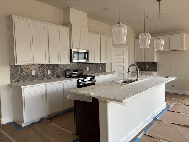 kitchen with a center island with sink, white cabinets, stainless steel appliances, and decorative light fixtures