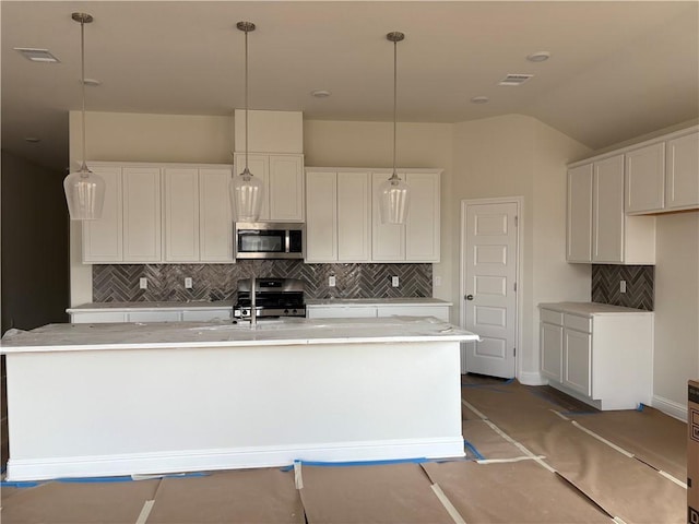 kitchen with white cabinets, stainless steel appliances, and an island with sink