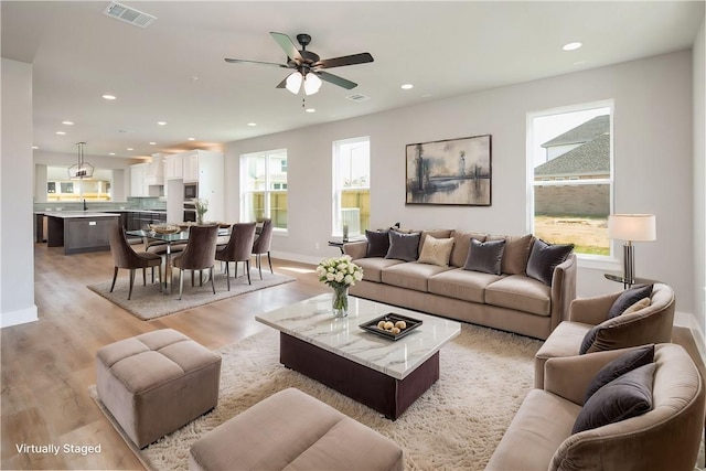 living room with light wood-type flooring, ceiling fan, and sink