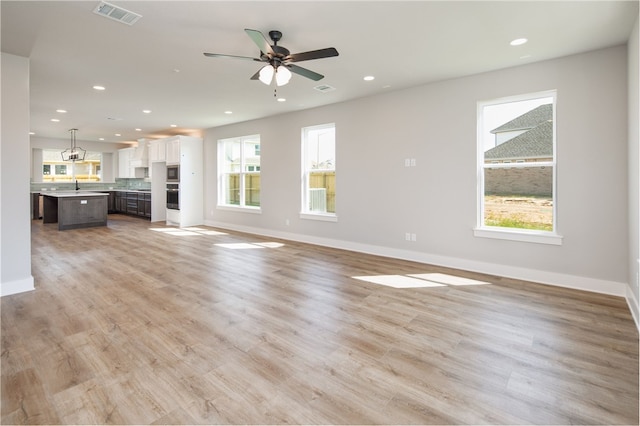 unfurnished living room with ceiling fan, plenty of natural light, light hardwood / wood-style floors, and sink