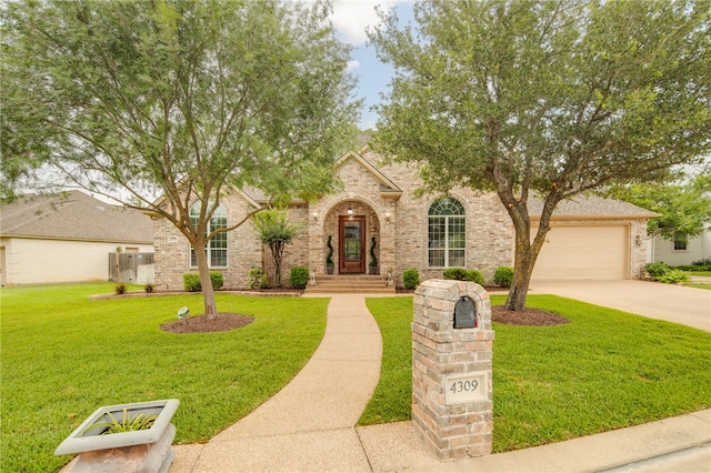 4309 Berwick Pl, College Station, TX 77845 - view of front of home with concrete driveway, a front lawn, a garage, and brick siding