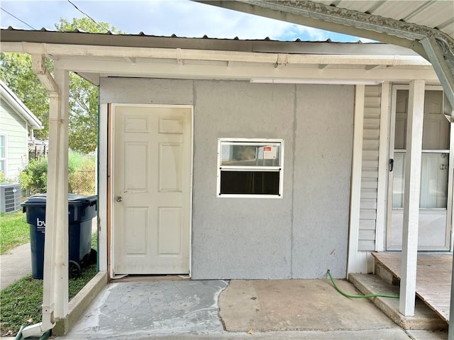 entrance to property with central air condition unit and stucco siding
