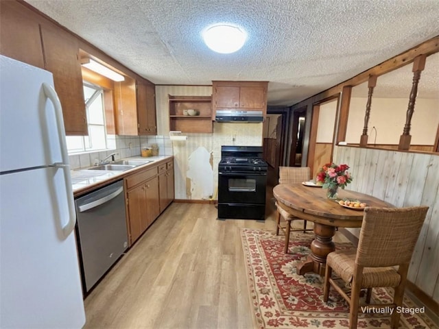 kitchen featuring black gas range oven, open shelves, freestanding refrigerator, under cabinet range hood, and dishwasher