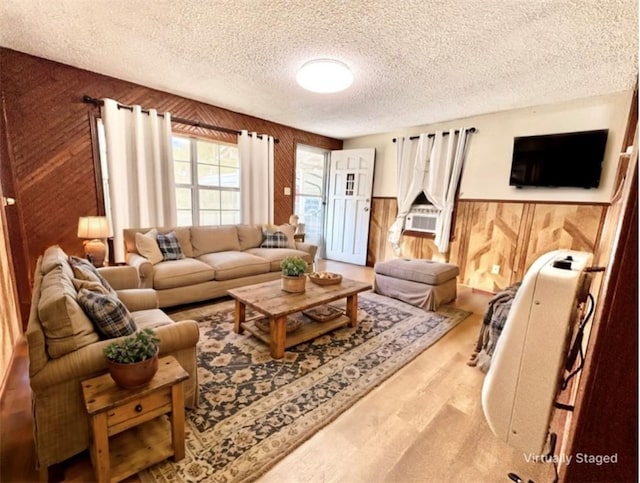 living room with wooden walls, wainscoting, a textured ceiling, and wood finished floors