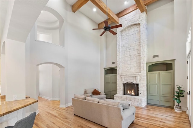 living room with beam ceiling, light hardwood / wood-style flooring, and a towering ceiling