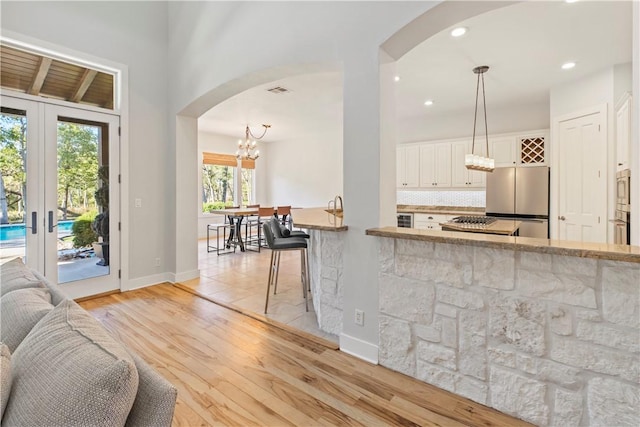 kitchen with appliances with stainless steel finishes, french doors, light hardwood / wood-style floors, and hanging light fixtures