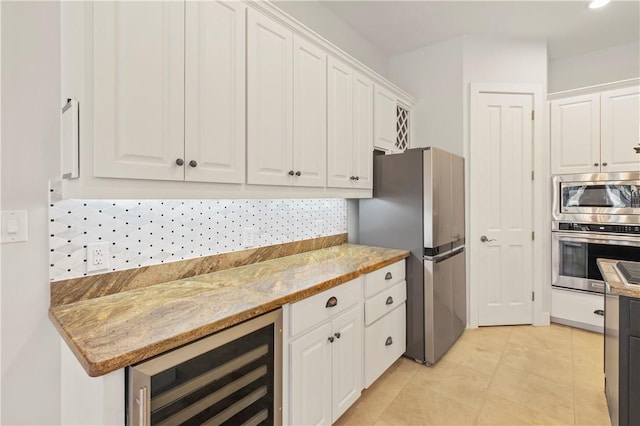 kitchen featuring white cabinetry, beverage cooler, light stone counters, and appliances with stainless steel finishes