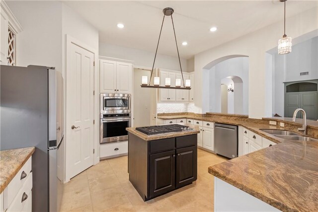 kitchen featuring appliances with stainless steel finishes, a kitchen island, sink, pendant lighting, and white cabinetry