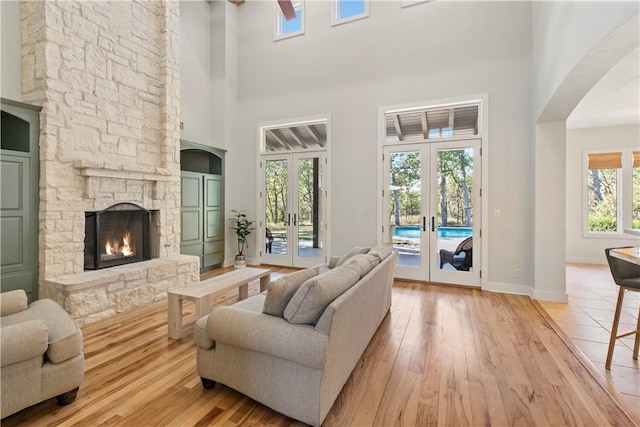 living room with french doors, light hardwood / wood-style flooring, plenty of natural light, and a high ceiling