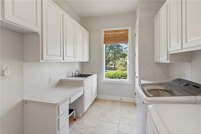 laundry area featuring cabinets, light tile patterned floors, washing machine and clothes dryer, and sink