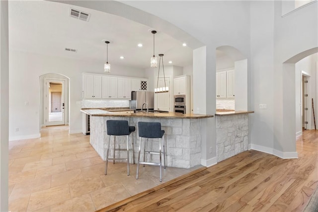 kitchen with decorative backsplash, light hardwood / wood-style floors, white cabinetry, and a breakfast bar area