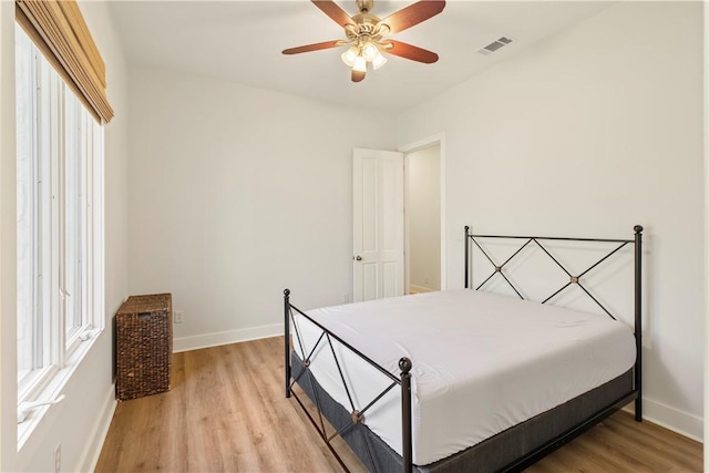 bedroom with ceiling fan, light hardwood / wood-style floors, and multiple windows