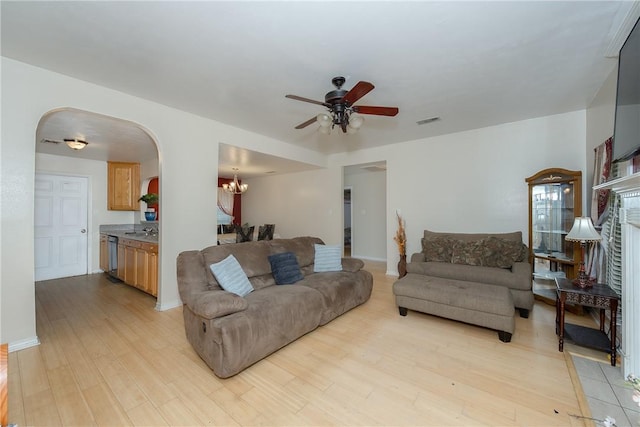 living room with sink, ceiling fan with notable chandelier, and light wood-type flooring