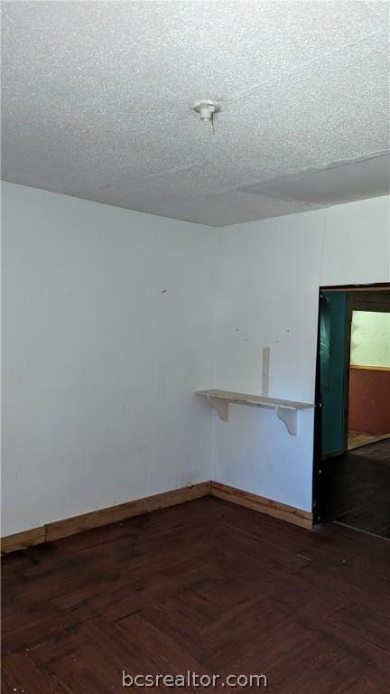 empty room featuring a textured ceiling and dark wood-type flooring