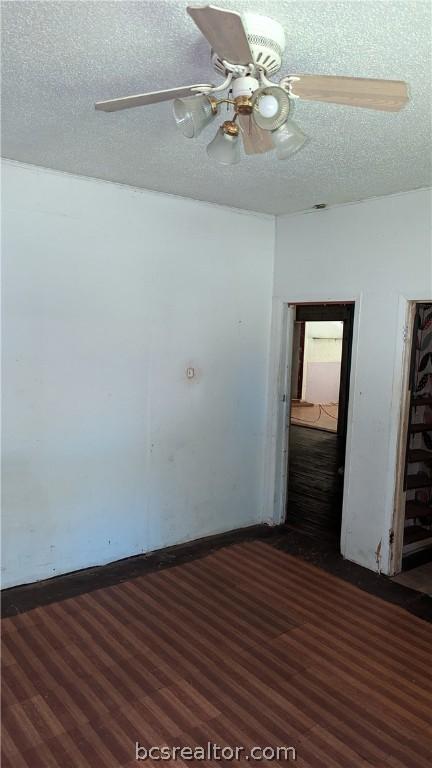 unfurnished room featuring a textured ceiling, ceiling fan, and dark wood-type flooring