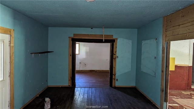 unfurnished room featuring a textured ceiling and dark hardwood / wood-style floors