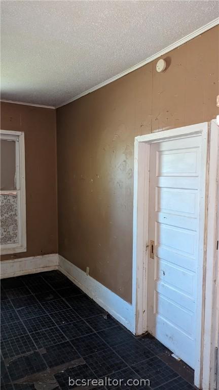 spare room featuring ornamental molding and a textured ceiling