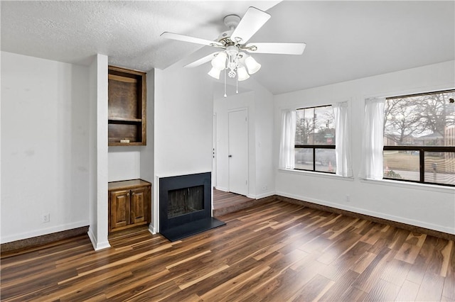 unfurnished living room featuring ceiling fan, dark wood-type flooring, and a textured ceiling