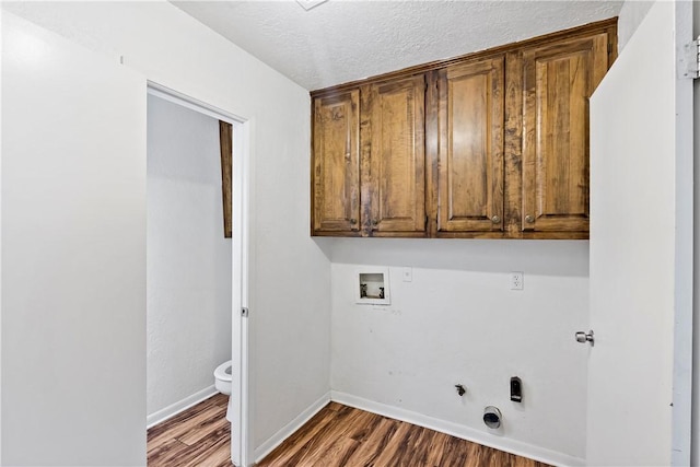 washroom with gas dryer hookup, cabinets, washer hookup, a textured ceiling, and dark hardwood / wood-style flooring