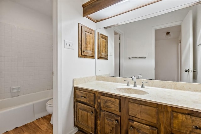 full bathroom featuring vanity, tiled shower / bath, wood-type flooring, and toilet