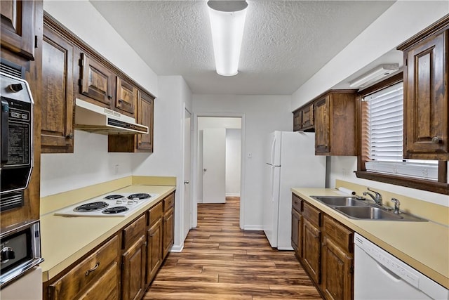 kitchen featuring sink, white appliances, dark hardwood / wood-style floors, and a textured ceiling