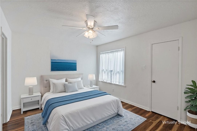 bedroom with ceiling fan, dark hardwood / wood-style flooring, and a textured ceiling