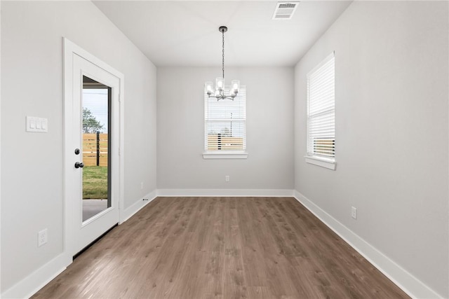 unfurnished dining area featuring a wealth of natural light, a chandelier, and dark hardwood / wood-style floors