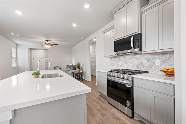 kitchen with gray cabinets, sink, an island with sink, and appliances with stainless steel finishes