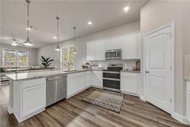 kitchen featuring pendant lighting, kitchen peninsula, ceiling fan, appliances with stainless steel finishes, and white cabinetry