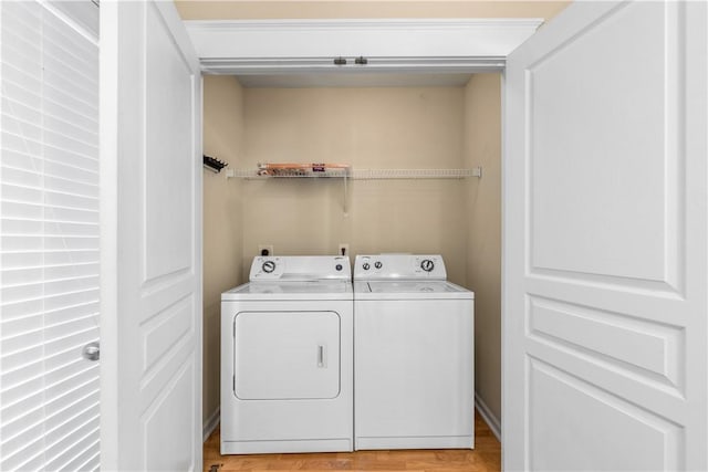 clothes washing area with light hardwood / wood-style floors and washing machine and clothes dryer