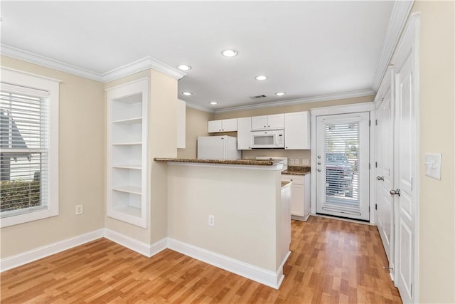 kitchen featuring light hardwood / wood-style flooring, kitchen peninsula, dark stone countertops, white appliances, and white cabinets