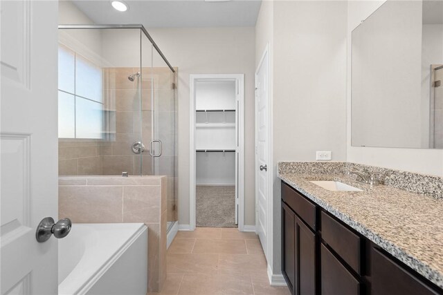 bathroom featuring tile patterned floors, a walk in closet, vanity, a shower stall, and a bath