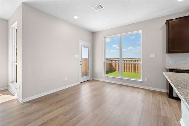 unfurnished dining area with light wood finished floors, visible vents, and baseboards