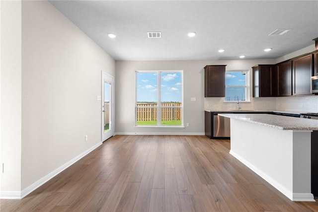 kitchen featuring light wood-style flooring, dark brown cabinetry, a sink, visible vents, and appliances with stainless steel finishes