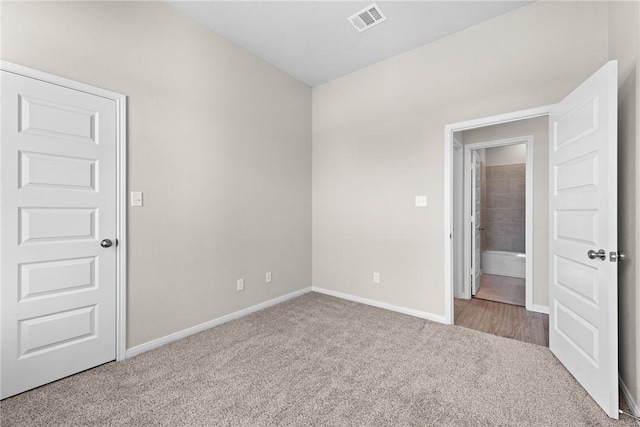 unfurnished room with carpet floors, visible vents, and baseboards