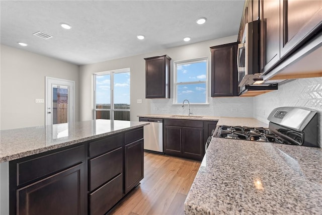 kitchen featuring light wood-style floors, appliances with stainless steel finishes, a wealth of natural light, and a sink