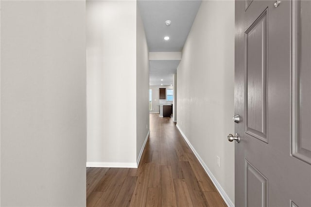 corridor with baseboards and wood finished floors