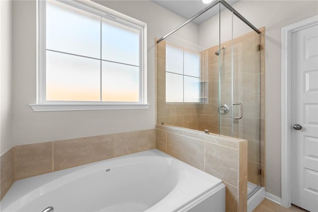 full bath featuring a healthy amount of sunlight, a garden tub, and a shower stall